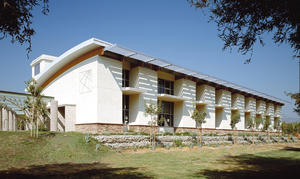 In this photograph, the building's south façade frames the edge of the park. Building articulation, lightshelves, overhangs, and louvers mediate daylight in the library reading room while framing views of the maple trees of the park. - Photo Credit: RMA Photography, Inc.