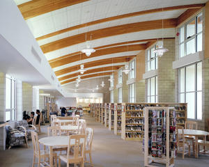 The main library reading room seating areas, shown in this photo, are located by windows looking onto the courtyard to the left and the public park to the right. Lightshelves at the south windows (at right) bounce light into the ceiling vault. Panels set between FSC-certified glu-lam beams temper acoustics in the room. - Photo Credit: RMA Photography, Inc.