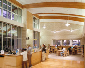Bamboo flooring marks the entry to the main reading room at the circulation desk, shown here. The young-adult section is beyond. Fins, overhangs, and the entry trellis protect the west windows set low in the burnished block walls. - Photo Credit: RMA Photography, Inc.
