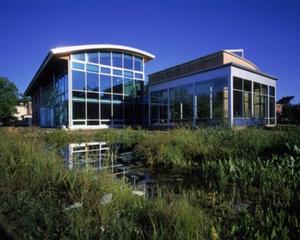 The Lewis Center is visible in this photograph beyond the constructed wetland. The main atrium is located in the taller, left-hand section. The greenhouse and Living Machine are housed in the right-hand, glassed-in section. The auditorium is located behind the greenhouse. - Photo Credit: Robb Williamson