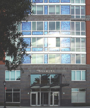 This photograph of the entry to 20 River Terrace shows the prominent placement of building-integrated photovoltaic panels and how they are an important design element in the building’s main façade. - Photo Credit: Cesar Pelli & Associates