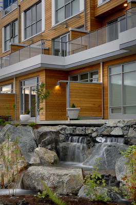 This photo shows townhouse patios as viewed from the Greenway, with a waterfall in the foreground. - Photo Credit: Vince Klassen