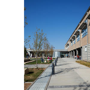 The courtyards shown in the photo features an outdoor eating area, a rainwater storage system on display, and a variety of gathering and play spaces. - Photo Credit: (c) Farshid Assassi