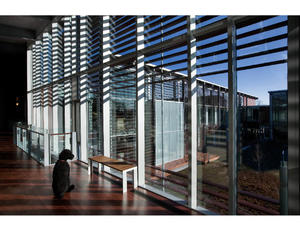 The full-height glass curtain-wall shown in this photograph strengthens the connection with the exterior landscape, increases views, and traps sunlight. The structural design of the Headquarters employs innovative strategies that allowed the architects to open the inside of the building out towards the central meadow. A row of columns along the curtain-wall was removed in favor of cantilevered floors and roof, where the glass and louvered shading system are suspended from above. The result is a building solved for lightness, efficiency, and direct connection to the landscape. - Photo Credit: © Peter Vanderwarker 2008