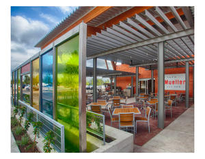 An outdoor cafe with a bar and bandstand are located at the store entry, establishing a public space that leverages Austin's climate and unique culture of enjoying live music outdoors - Photo Credit: Mark Gaynor