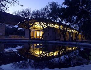 The building was sited to provide low impact to the site. This photo shows the building nestled between stands of trees and next to the wildlife cistern. - Photo Credit: Greg Hursley
