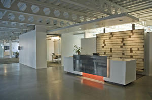 The primary tenant’s reception area features an art wall created with salvaged wood floor decking from the building that previously occupied the site. - Photo Credit: Gabe Hanson