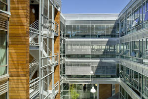 This is a photograph of the courtyard from level three looking north at the exterior blinds, green screen stair, automatic louvers, and operable windows. - Photo Credit: Lara Swimmer