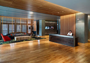 The office reception area is used for multiple functions with moveable furniture and doors opening onto an outdoor deck. The large reception desk in the lobby was crafted out of salvaged Oregon walnut and hand-crafted locally without any fasteners. - Photo Credit: Basil Childers