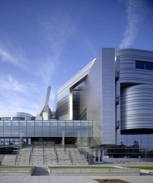 The metal wall panels, shown in this photo of the main entrance, incorporate recycled material; the large wall of windows brings daylight into the open atrium. - Photo Credit: Tim Griffith