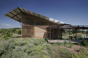 This photo shows the view from the outdoor classroom area looking east toward the exhibit space. The exhibit space opens up to views and light to the north. Southern sun is blocked by a broad roof overhang. - Photo Credit: Chris Cooper