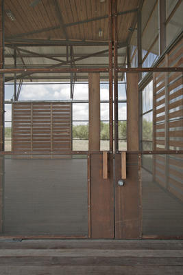 The unconditioned exhibit space, shown in this photo, opens to cooling breezes and views beyond. Rolling doors close to block out winter winds, and exhibits roll away to allow for flexible multipurpose use. - Photo Credit: Chris Cooper