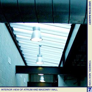 This photograph shows an interior view of the atrium and its masonry wall. The mass of this wall serves as a heat sink, helping to heat the atrium and the offices. - Photo Credit: Cybul and Cybul Architects