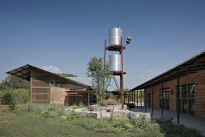 The rainwater storage tower, shown in this photo, uses a solar-powered pump and gravity for water distribution. - Photo Credit: Chris Cooper