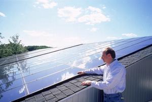 In this photo, Paul Torcellini of NREL examines the 14.3 kW PV system on the roof that offsets some of the power use of the building. - Photo Credit: Robb Williamson