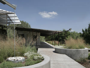Rainwater collected from roofs is filtered through gravel caps and conveyed to underground cisterns, shown in this photo, which double as seats and native-grass planters along the public entryway. - Photo Credit: Chris Cooper