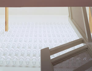 The wall of water bottles, shown here, acts as a heat sink in the solar chimney. Augmented by a whole-house fan, the shaft will pull warm air up and out of the house in the summer, and push warm air down in the winter. - Photo Credit: Doug Snower Photography